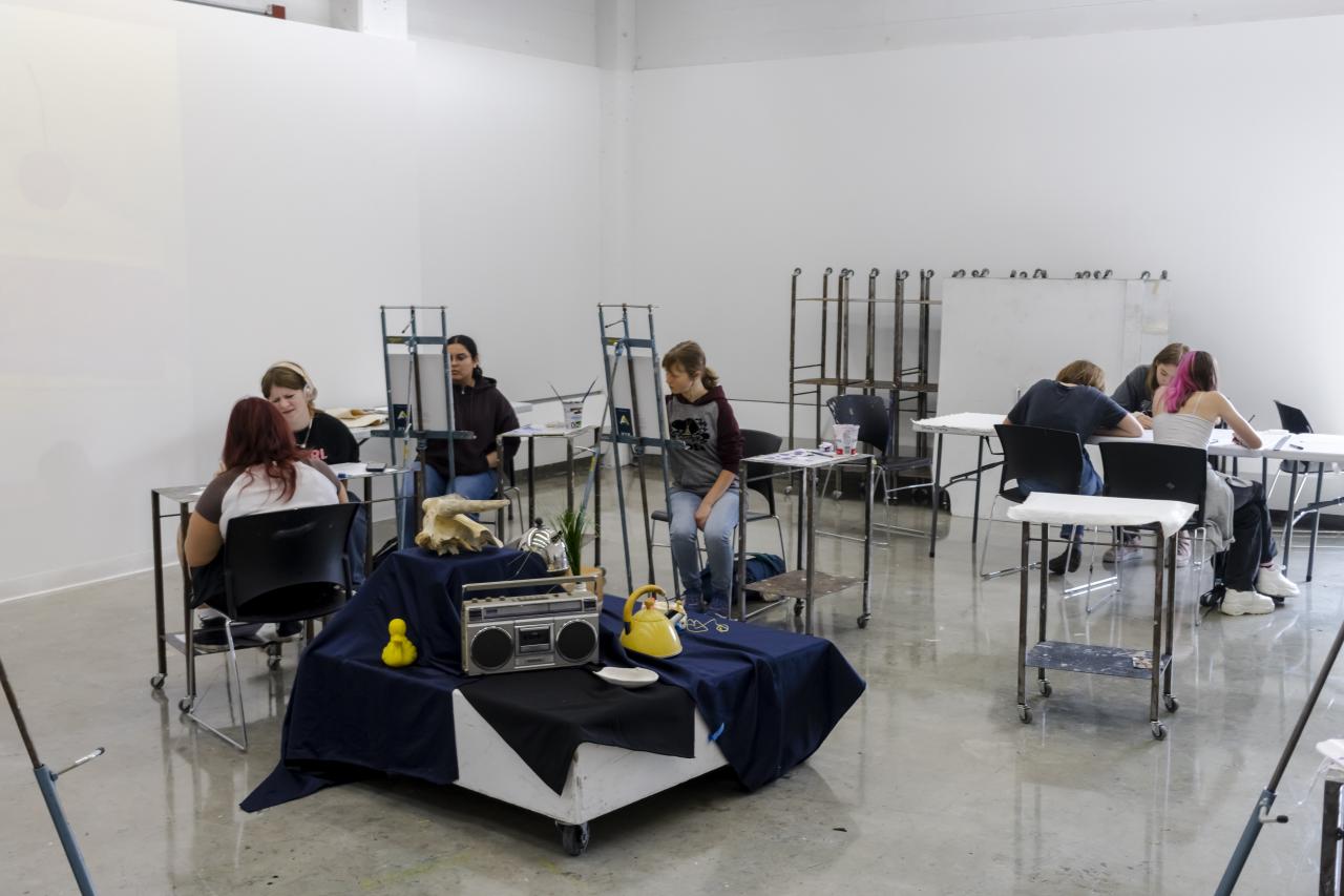a group of young students painting at easels in a bright studio