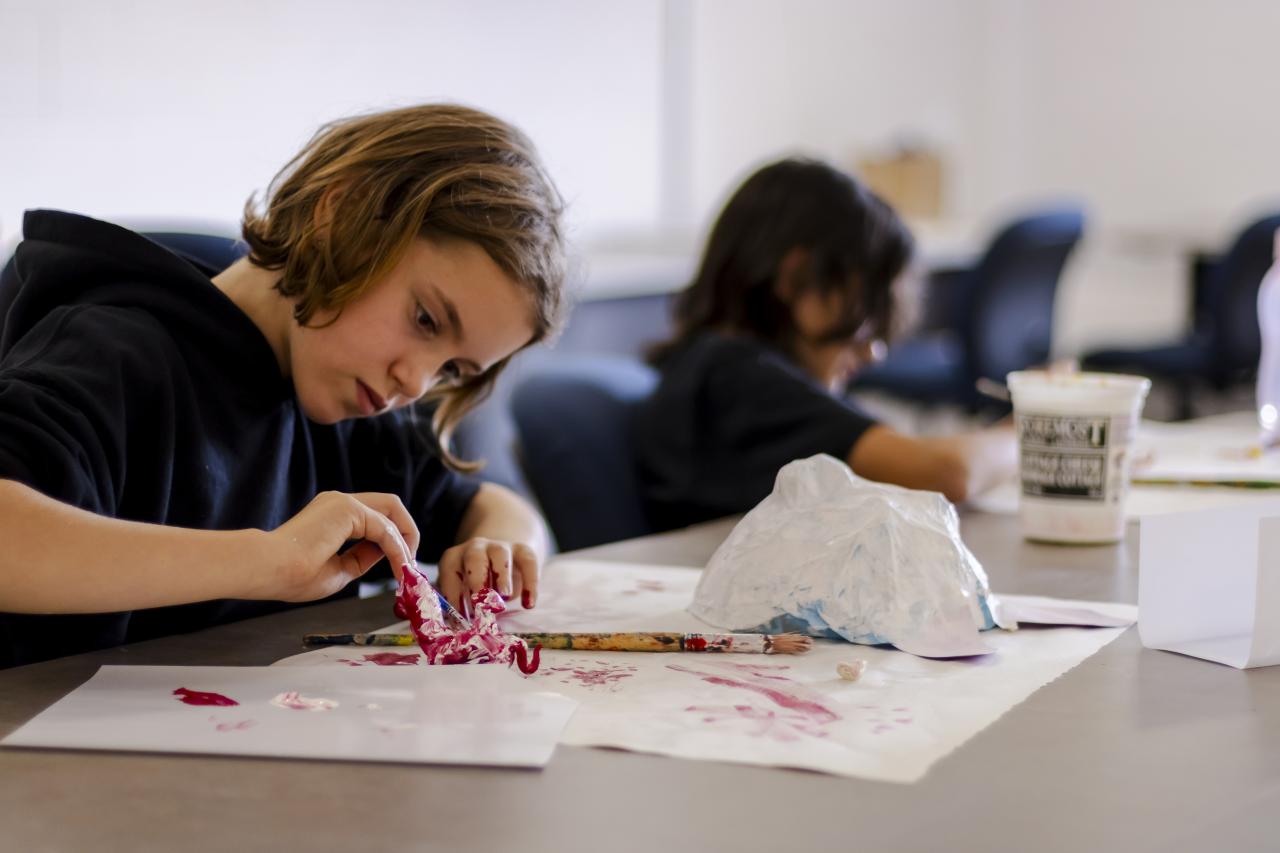 2 kid camp students working on their art project at a table in a brightly lit studio