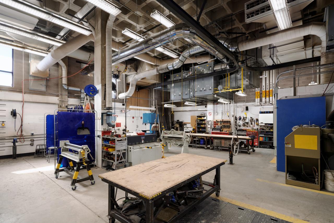 Metal Shop 1 Wide view of AUArts metal shop with work tables, welding stations, ventilation systems, and industrial equipment.