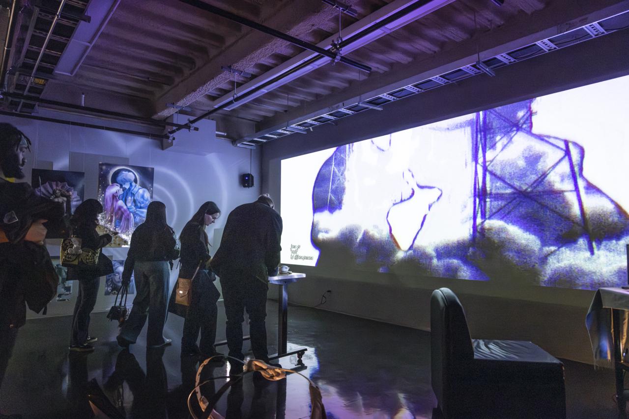 Gallery visitors experience an immersive video projection installation with purple lighting during an Alberta University of the Arts exhibition.