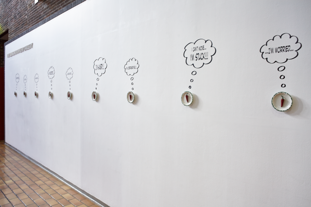Outside of IKG, gallery wall with peppers on plates. Each pepper has a vinyl thought bubble
