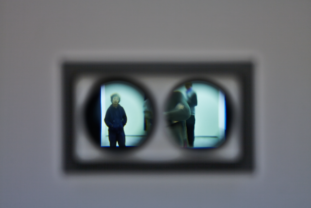 Detail of the peephole lenses. This shot shows the how through the lenses we see the public milling around. 