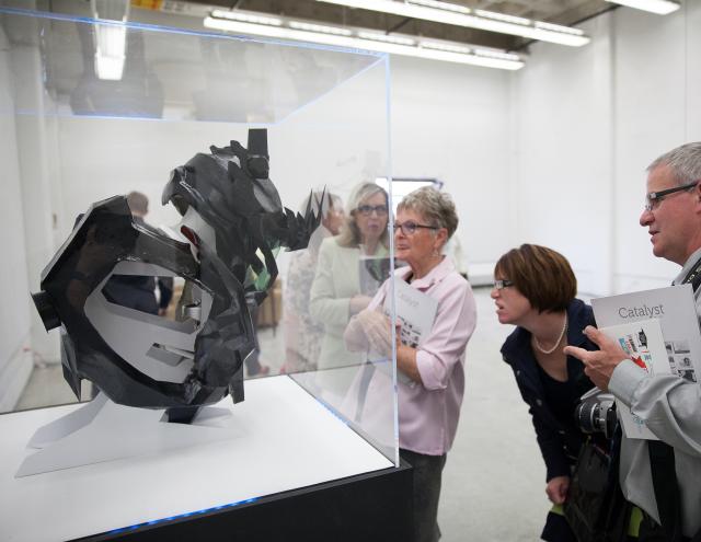 A group of guests looking into a display case with a medium scale object staring out.