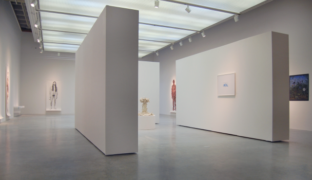 Wide angle of the gallery. Moving toward the left of the previous image there are two floating walls visible activating three corridors. There are six drawings visible from this angle. 