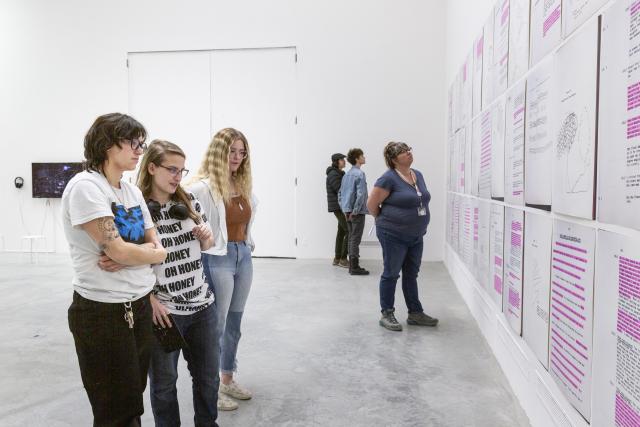 Six people looking at art from The Beyond Within that is hanging on the wall