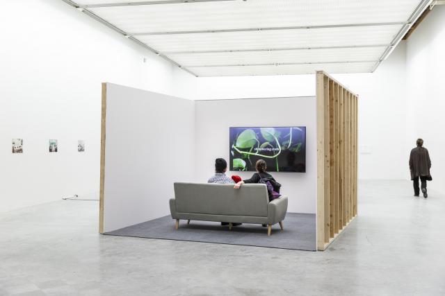 Two adults and a child sit on a couch watching a screen that says "shimmering cloth" from The Beyond Within