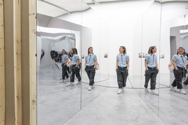 Person walking between two mirrors as their image is reflected back at them in a repeating pattern