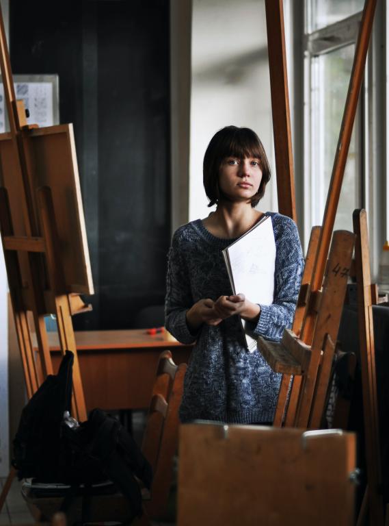 person standing in paint studio surrounded by easels 