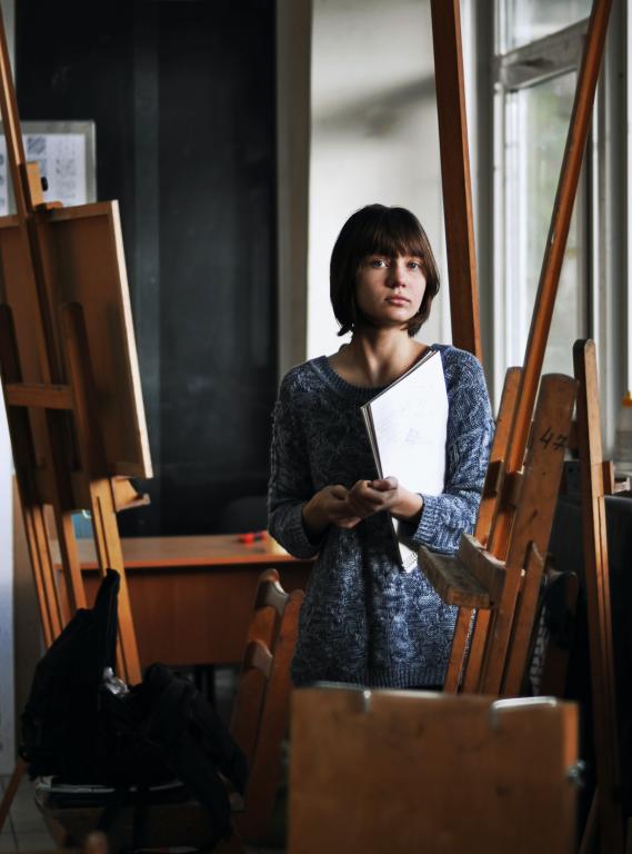person standing in paint studio surrounded by easels