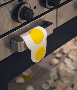 Detail of drooping egg on stove handle.
