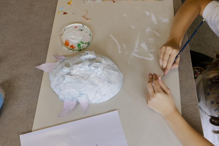 Kids camp student painting a cat shaped mask