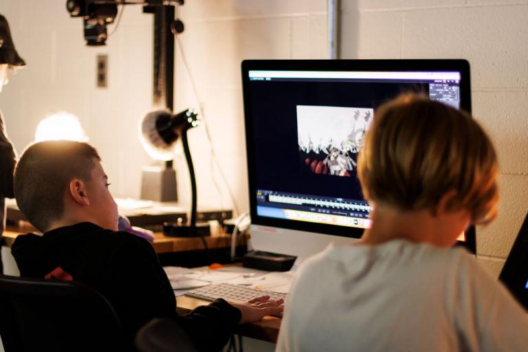 a group of kid camp animation students work on creating an animation at a computer