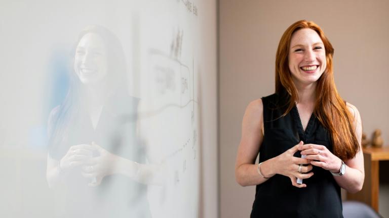 a woman in front of a whiteboard